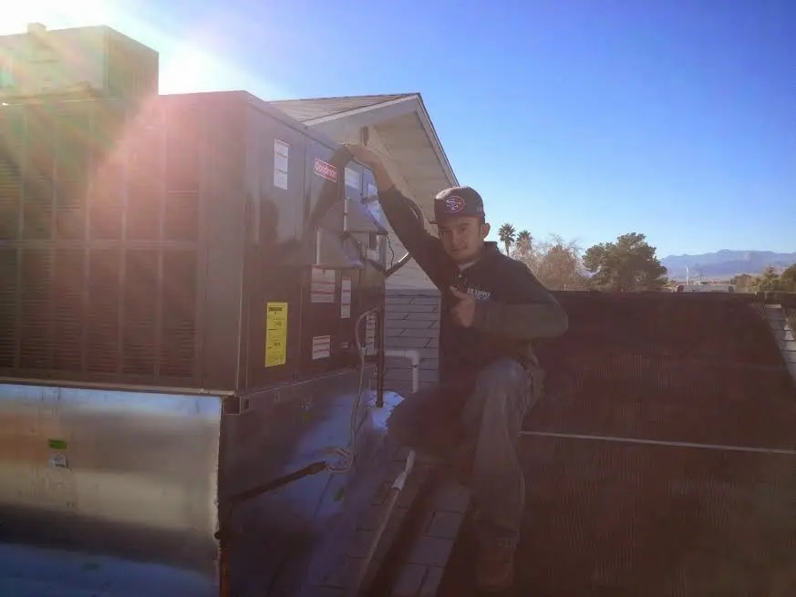 HVAC technician performing AC Tune-Up on a rooftop unit in Fulton