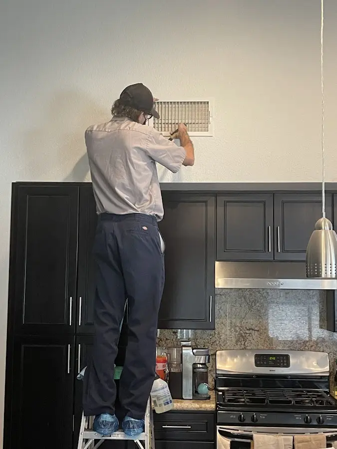 Technician inspecting an air vent during HVAC service in Fulton